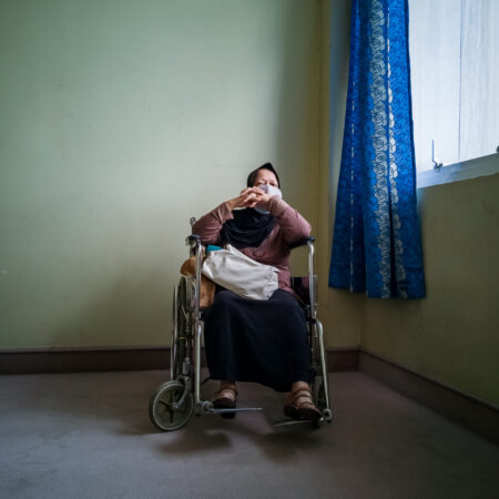 Portrait of a senior woman wearing hijab on wheelchair in a hospital.